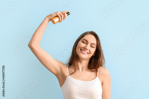 Young happy woman spraying essential oil on color background