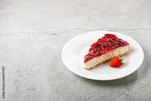 Strawberry glazed cheesecake on white dinnerware on the table.