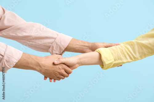 Man shaking woman's hand on blue background
