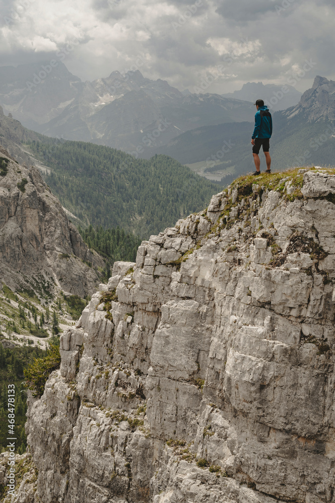 Man in Blue jacket standing on a Dolomite mountain in Italian alps with mountains in background