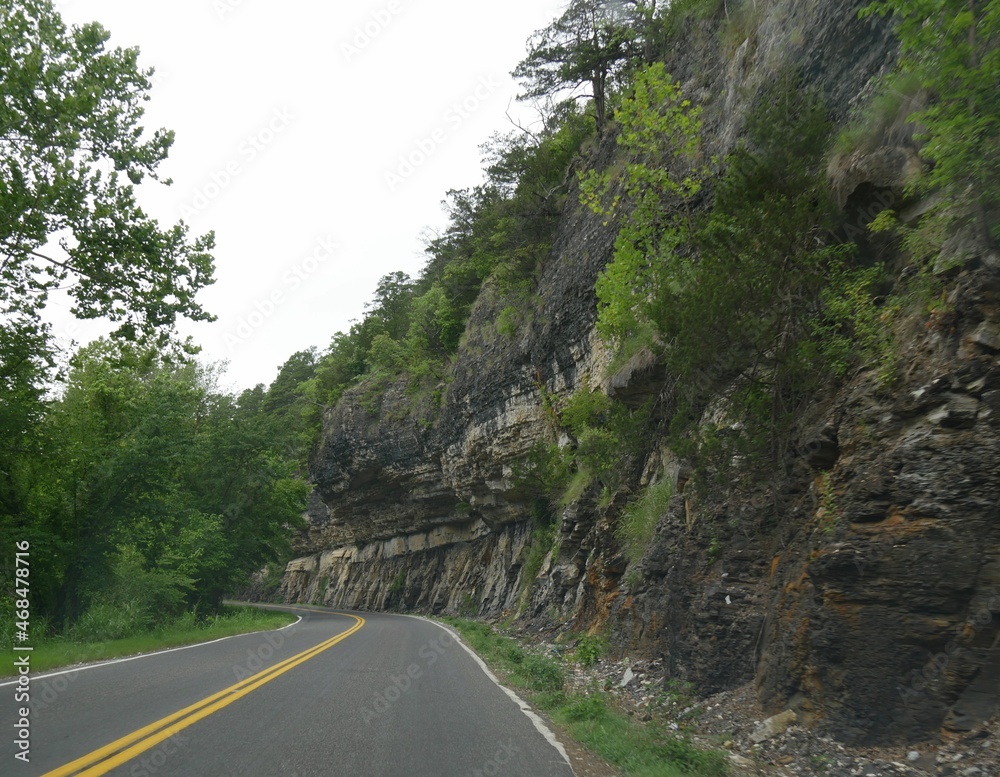 Scenic winding road with a solid rock wall at the foothills of Ozard Mountains in Oklahoma Scenic winding road with a solid rock wall at the foothills of Ozard Mountains in Oklahoma