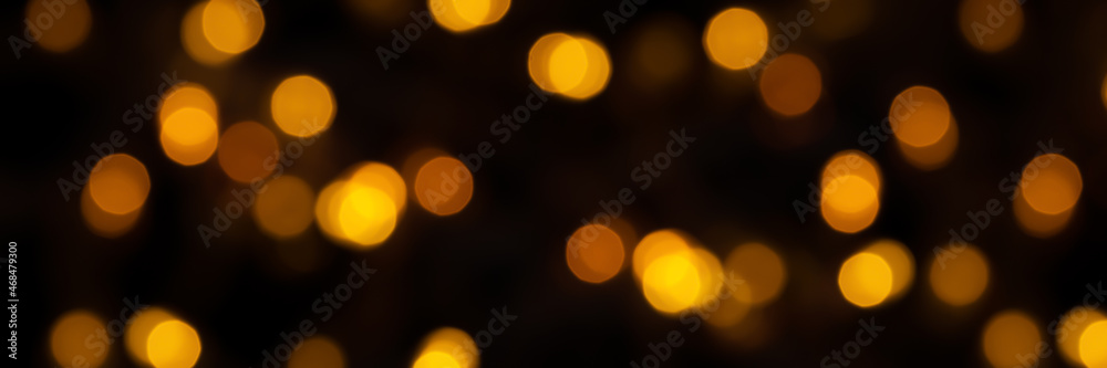 Fototapeta premium Banner of defocused bokeh lights on black background, an abstract naturally blurred backdrop for Christmas eve or birthday party. Festive light texture. Gold garland in blur. Overlay effect for design