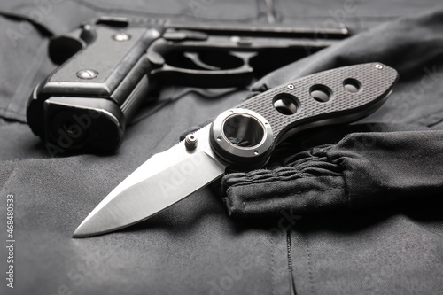 Folding pocket knife with pistol on black suit background