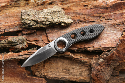 Foto Folding pocket knife with rubberized handle lying on tree barks
