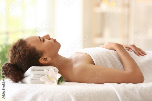 Young African-American woman lying on couch in spa salon