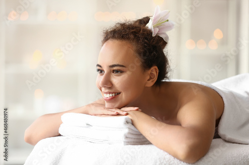 Young African-American woman lying on couch in spa salon