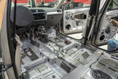 Car interior inside with seats and upholstery removed. Preparing for repair work or installing noise insulation soundproofing on modern SUV.