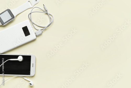 Modern power bank, smartwatch and mobile phone on beige background