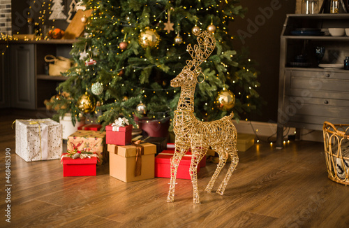 in the New Year's interior, there is a large figure of a deer on the background of a green Christmas tree.