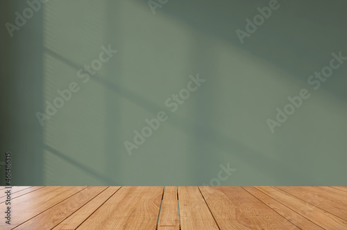 3D rendering of an empty shiny wooden counter top for products display in front of dark green wall inside an empty room with sunlight shining through blind curtain. Background, Table, Design, Concept.