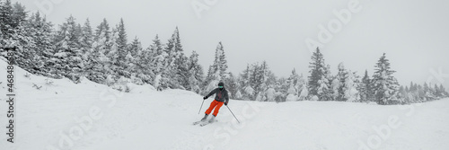 Skiing in idyllic mountain winter forest snow landscape. Man skiing on beautiful ski slopes on ski holidays travel vacation. Panoramic banner