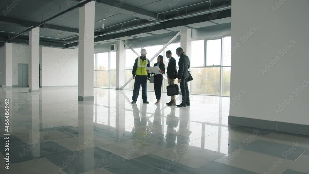 Business team are talking and looking around modern glass wall building standing inside discussing construction together. Real estate and commerce concept. Business team are talking and looking around modern glass wall building standing inside discussing construction together. Real estate and commerce concept.