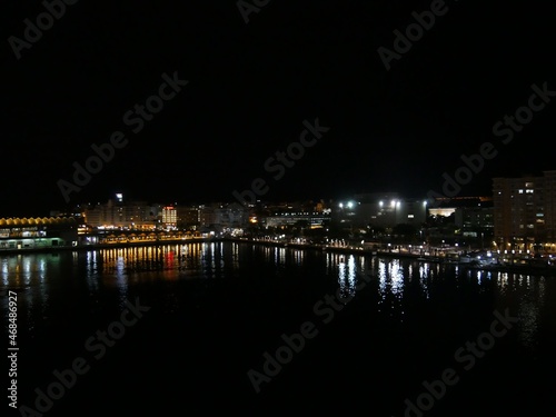 Medium wide shot of the seaport of Puerto Rico at night, with colorful lights reflected in the waters © raksyBH