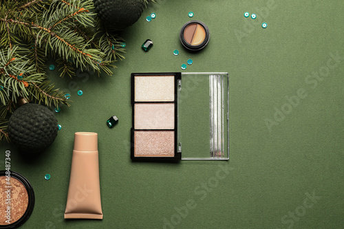 Decorative cosmetics, fir tree branch and Christmas balls on green background