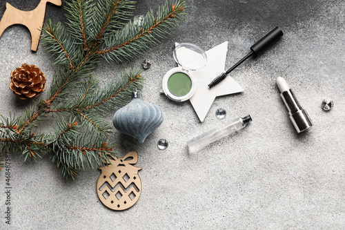 Makeup cosmetics with Christmas decor and fir branch on grey background