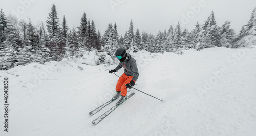 Skiing man. Alpine ski - skier going dowhill against snow covered trees background in winter nature landscape. Ski holidays vacation concept