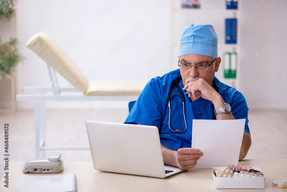 Old male doctor working in the clinic Old male doctor working in the clinic
