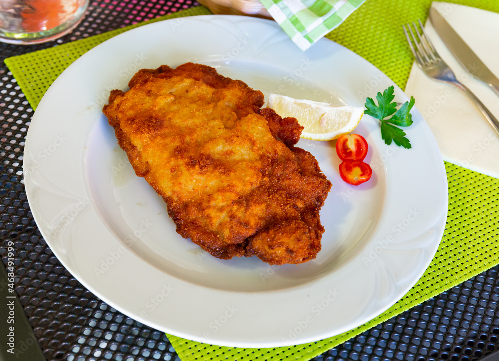 Tasty pork steak ljubljana stuffed with cheese and ham at white plate