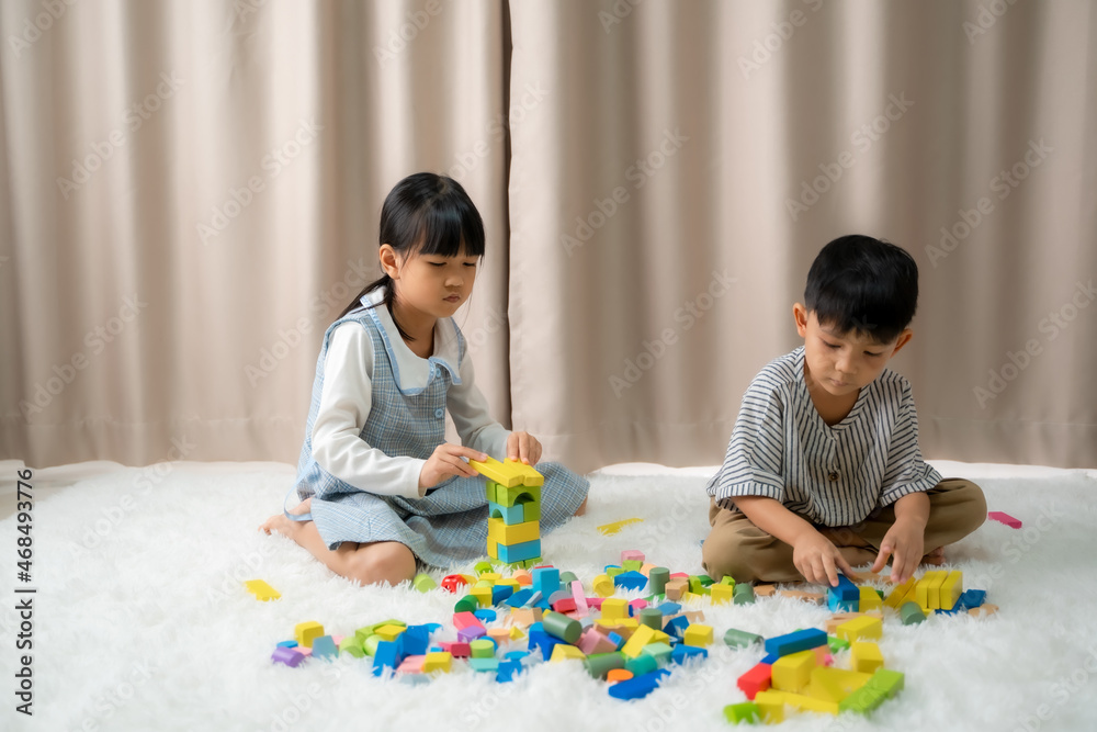 Children is happy to play toy building blocks while sitting on carpet at home. Children is happy to play toy building blocks while sitting on carpet at home.