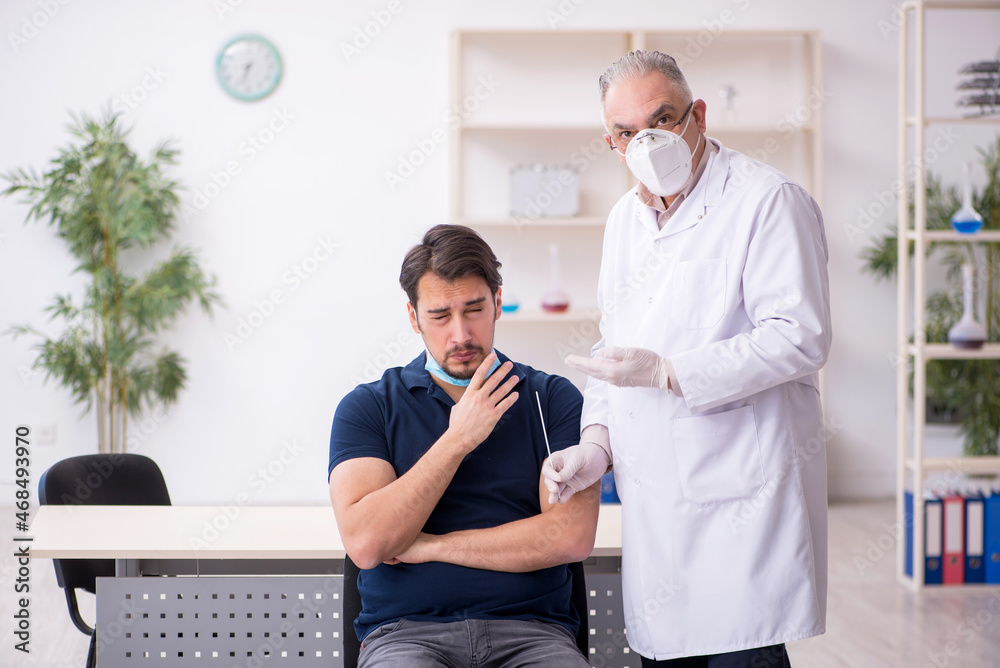 Fototapeta premium Young male patient visiting old male doctor during pandemic