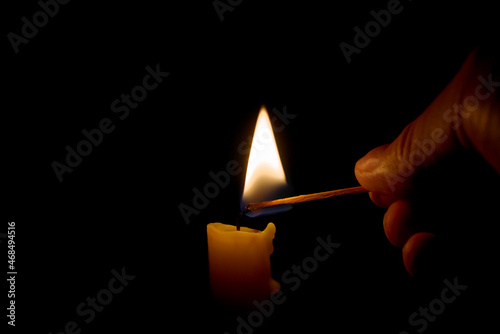 Burning candle in the darkness. Lighting candle with match.
