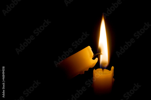 Burning candle in the darkness. Lighting candle with another one.