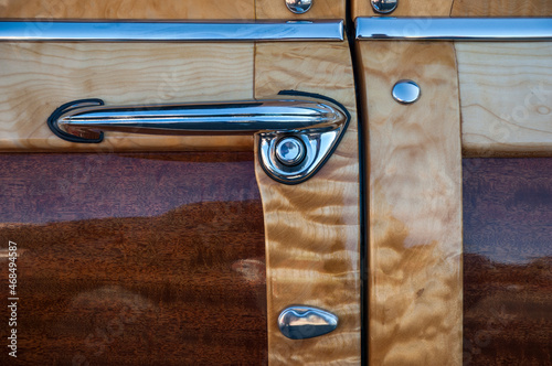 Vintage woody automobile showing the detail just the door handle isolated with wood panelling and with lock and trim. photo