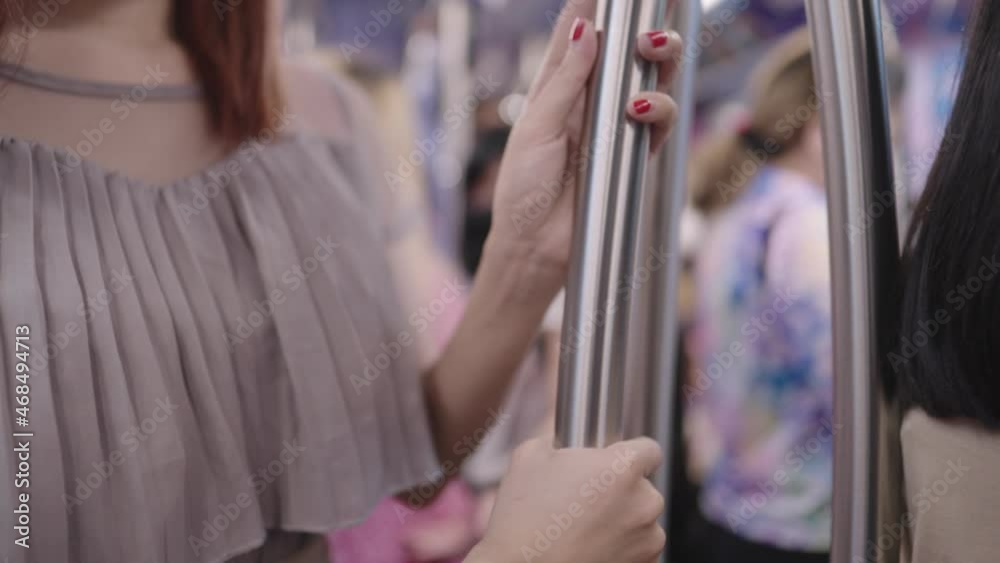 Close up a female red fingernails hand holding on metal rail to prevent from falling, safety equipment on public transportation, domestic life, a risk of contamination to infectious covid-19 diseases Close up a female red fingernails hand holding on metal rail to prevent from falling, safety equipment on public transportation, domestic life, a risk of contamination to infectious covid-19 diseases