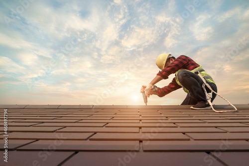 Fotografia Roofer working in special protective work wear gloves, using air or pneumatic na