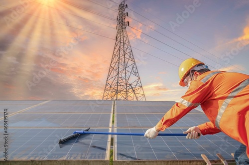 Electrical engineers industry checking installing or cleaning photovoltaic plant in solar power station alternative nature energy High voltage pole background.Renewable energy and solar power concept