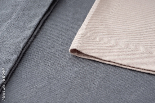 T-shirt sleeves close-up, copyspace, mock up, flat lai, top view. Ready-made T-shirt made of dark gray and beige thick cotton. Background of natural fabrics, texture. Elements of fashion clothing