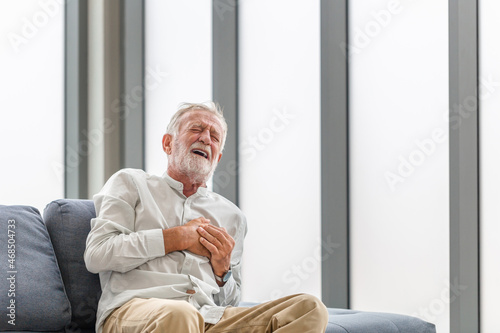 Mature man presses hand to chest has heart attack suffers from unbearable pain, Senior man with pain on heart in living room