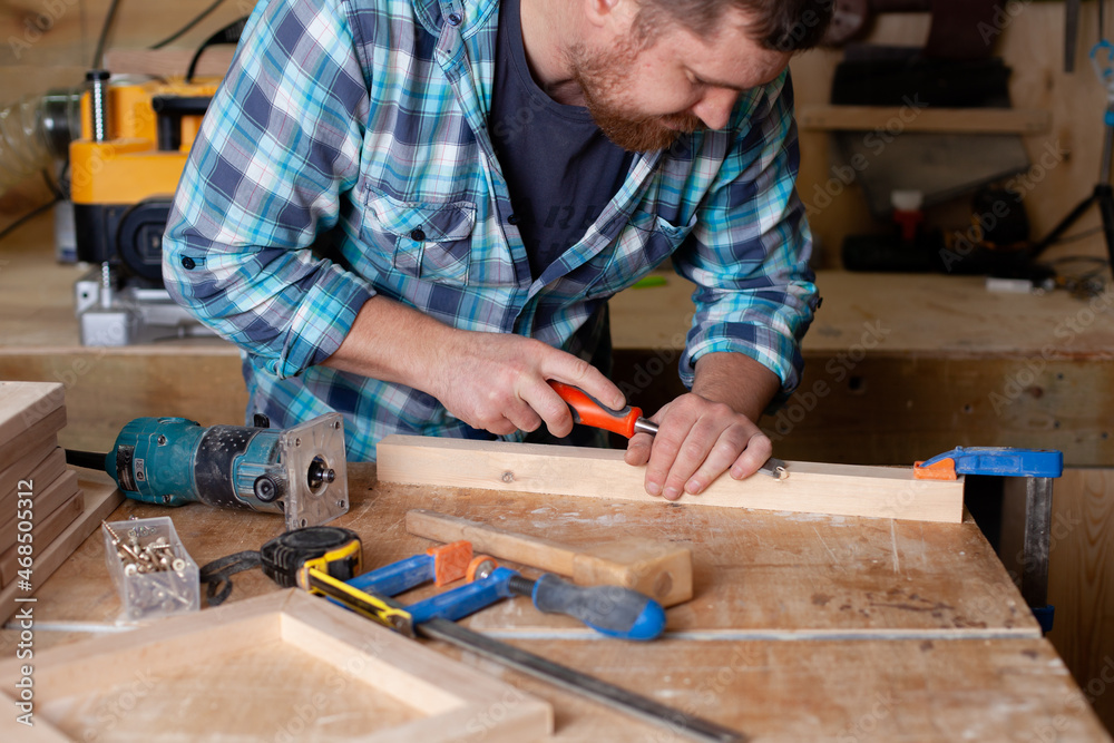 A bearded carpenter in a plaid shirt works a workshop. Wood. Ecological compatibility. Lifestyle. A bearded carpenter in a plaid shirt works a workshop. Wood. Ecological compatibility. Lifestyle.