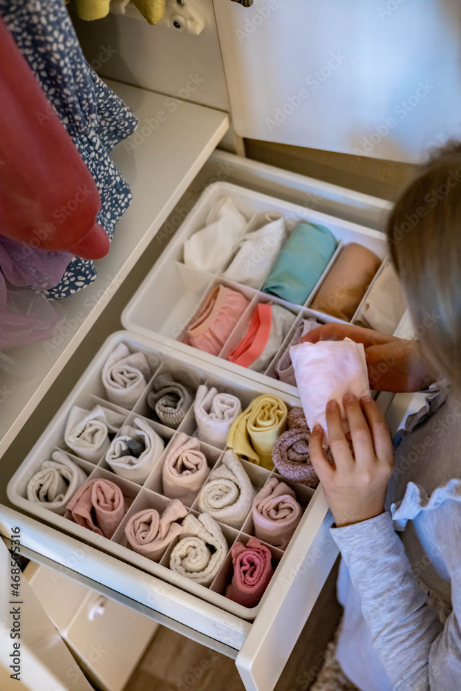 Female hands organizing storage of underwear socks t shirts use Marie Kondo's method. Perfectionist Teenage girl