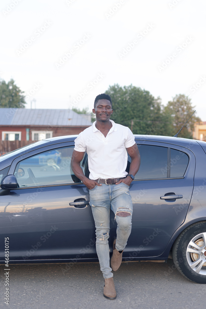 A happy African-American man near a car. Car sales and rentals A happy African-American man near a car. Car sales and rentals