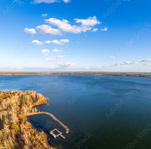 Colorful autumn forest with trees on the shore of a blue lake - top aerial view. © Dmitrii Potashkin