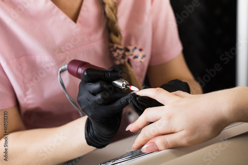  A manicurist removes gel polish from nails using a milling cutter. Hardware manicure close-up. Coating shellac on nails