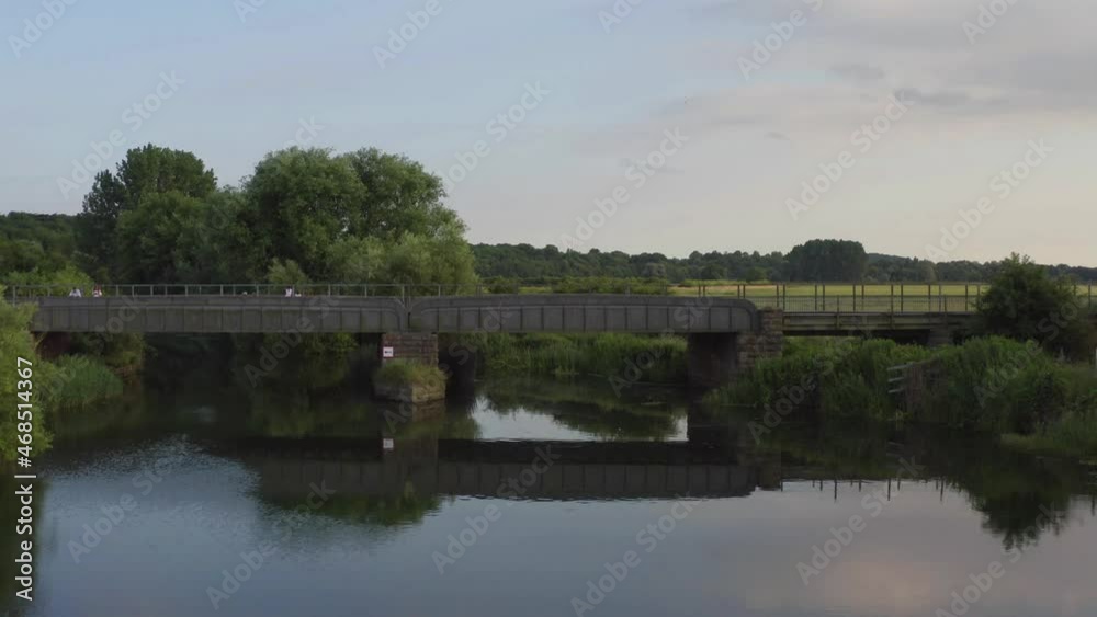 Side view of the railway track over a green meadow; dense forest enclosing a farmland. Side view of the railway track over a green meadow; dense forest enclosing a farmland.