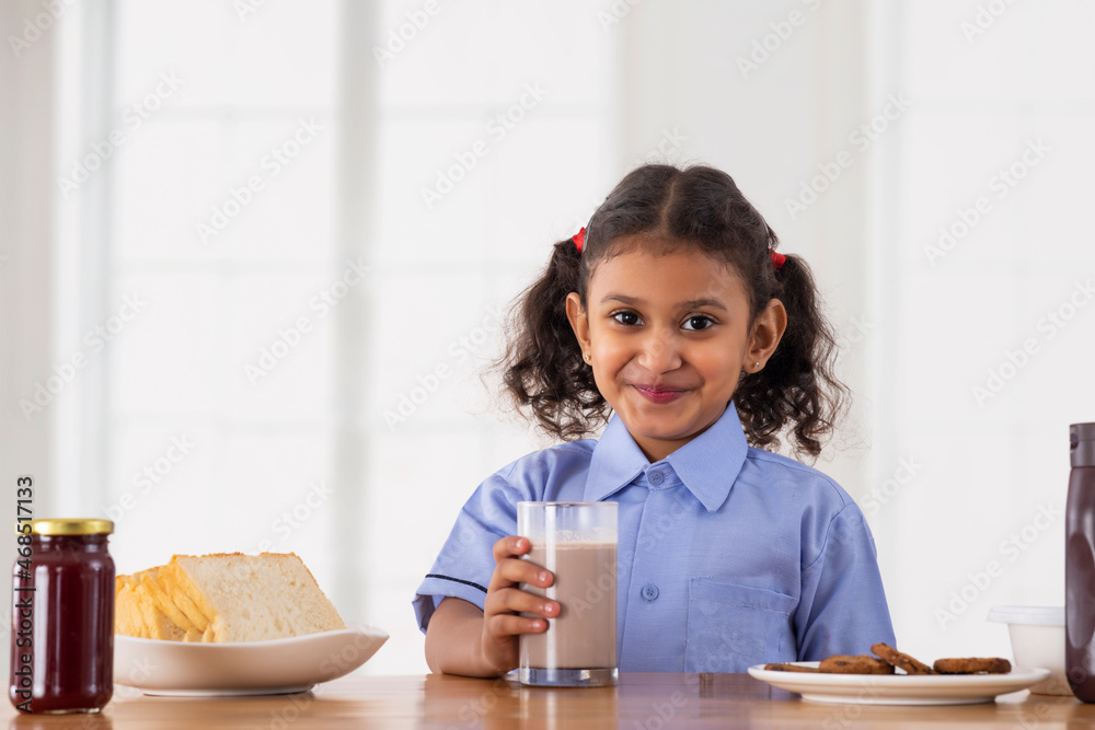 Beautiful Girl in school uniform posing in front of camera while holding a glass of chocolate milkshake Beautiful Girl in school uniform posing in front of camera while holding a glass of chocolate milkshake