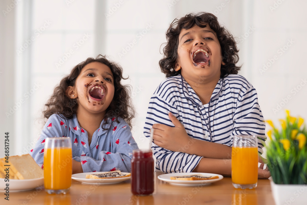 Sibling having fun in front of camera during their breakfast 