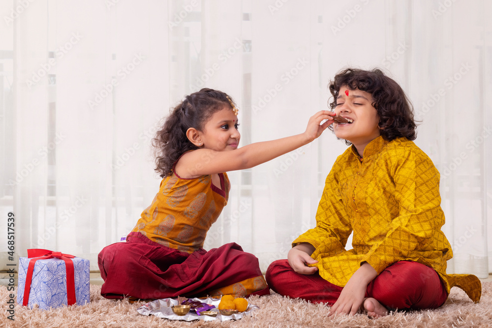 Girl giving her brother bite of chocolate on Bhai Dooj Stock Photo
