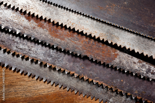 Old vintage metal saws for wood of different shapes and sizes, crumpled on a wooden background.