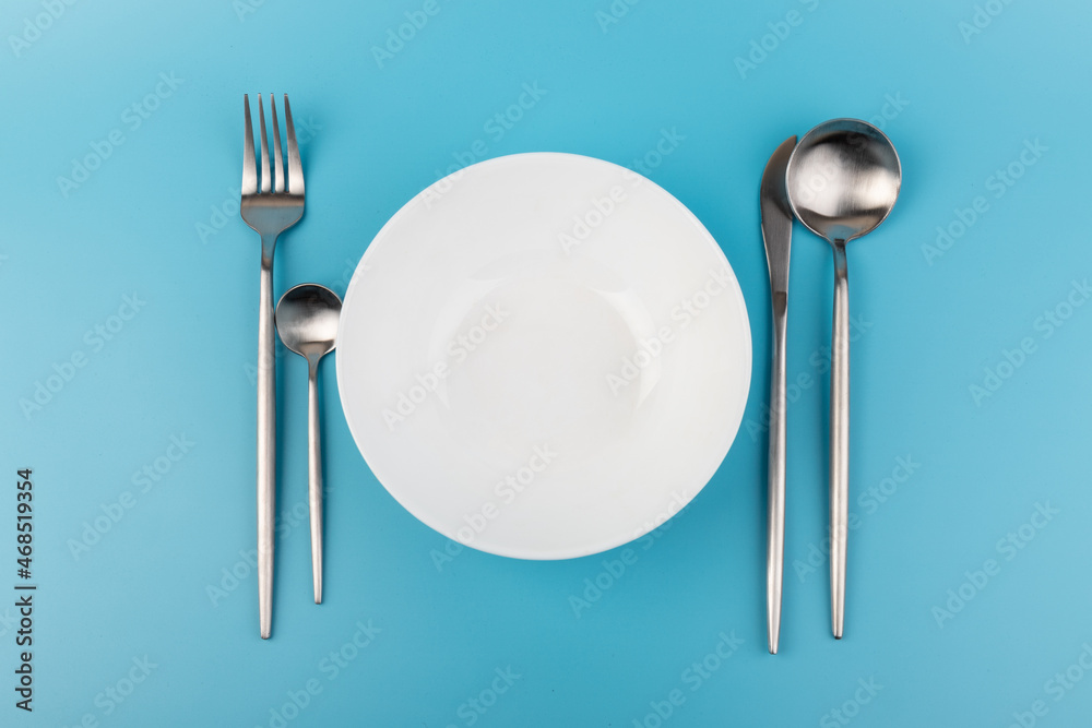 Empty plate with fork and spoon on blue background. Flat lay Dishes for breakfast, lunch or dinner Mock up Empty plate with fork and spoon on blue background. Flat lay Dishes for breakfast, lunch or dinner Mock up