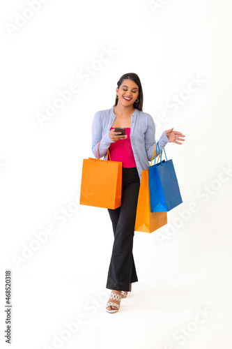 Beautiful young lady with shopping bags and holding mobile in her hand