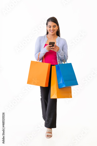 Beautiful young lady with shopping bags and holding mobile in her hand