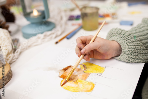 The girl paints with watercolors at the Christmas master class. Education and creativity of children at school. Young artist draws a sketch