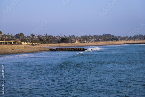 Fototapeta Naklejka Na Ścianę i Meble -  a gorgeous shot of the vast blue ocean water and silky brown sand at the beach with waves rolling in and blue sky at Surfers Point at Seaside Park in Ventura California USA