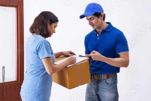Smart Indian woman signing a home delivery receipt of a package at the time of delivery