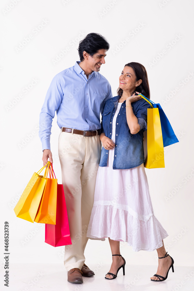 Indian middle age couple standing together with shopping bags Indian middle age couple standing together with shopping bags