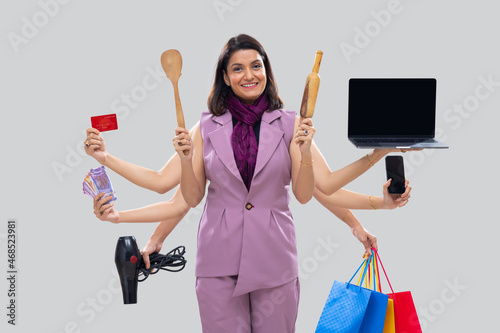 Portrait of a multitasking woman housewife with multiple hands holding various objects photo